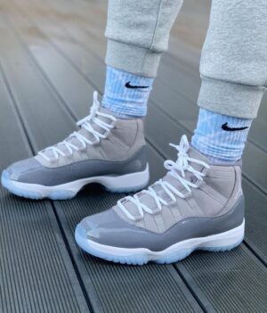 Air Jordan 11 Cool Grey 2022 sneakers with white and grey design, on wooden deck.