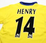 Official Arsenal Henry 14 away football jersey, yellow with black number 14 and team logo.