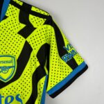 Official Arsenal away football kit for kids 2023/24 season, vibrant yellow and black design.