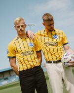 Brighton away football jersey 2024/25 with yellow and black stripes, featuring Brighton club logo an.