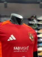 Al Ahly SC training jersey in red with team logo and Adidas branding, perfect for fans and players.