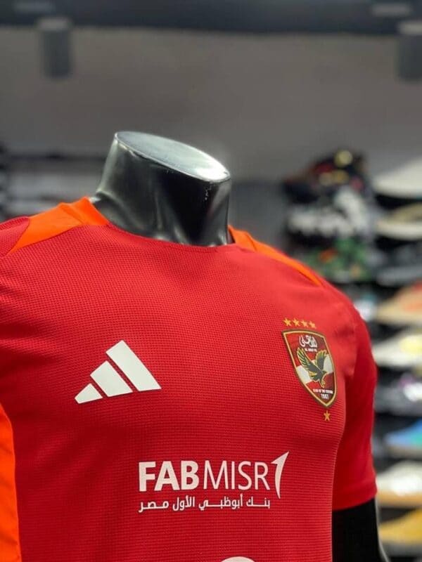 Al Ahly SC training jersey in red with team logo and Adidas branding, perfect for fans and players.