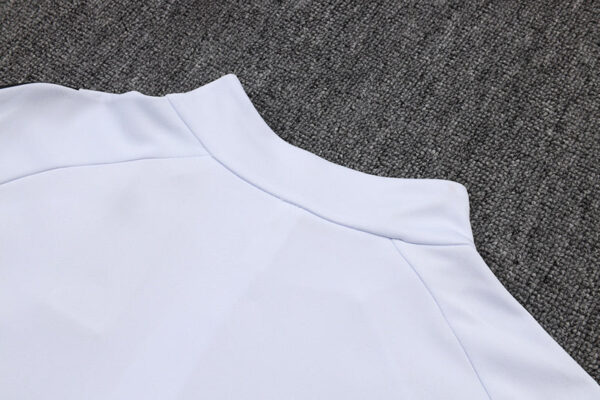 Close-up of white Adidas tracksuit top fabric and stitching details.