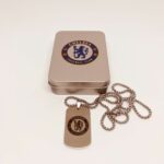 Chelsea FC logo dog tag with chain, authentic football club accessory in a metal storage box.