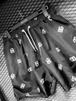 Black swim shorts with DG logo print, perfect for beach and pool activities.