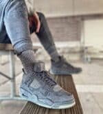 KAWS × Air Jordan 4 Retro 'Cool Grey' sneakers on a wooden bench.