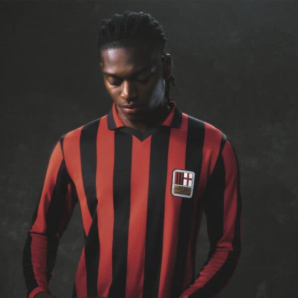 Milan football jersey with red and black vertical stripes, featuring club crest. Perfect for fans an.