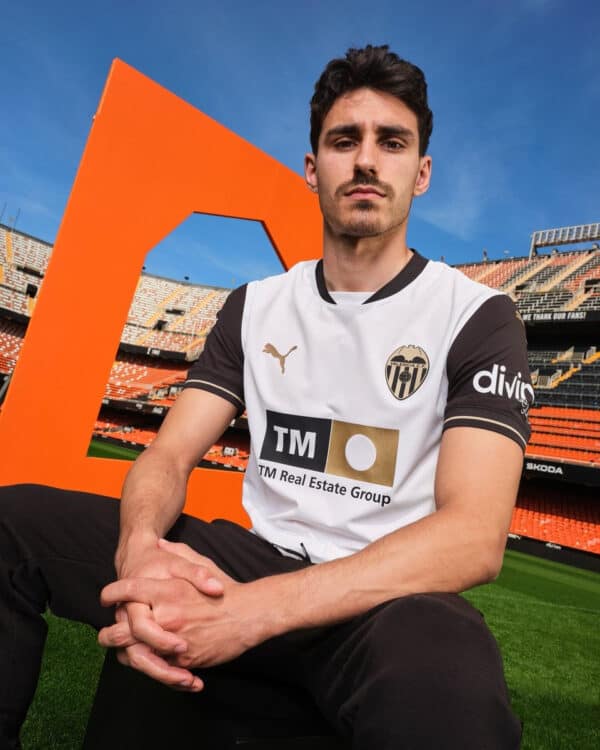 Valencia CF football player wearing official jersey at stadium, promoting authentic sports apparel f.