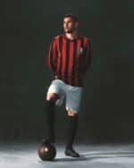 Athletic male soccer player wearing red and black striped jersey, white shorts, and black socks with.