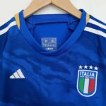 Official Italy youth football jersey for 2023/24 season, featuring team crest and vibrant blue desig.