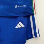 Italy kids home football kit 2023/24 with team logo and authentic design.