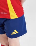 Kids Spain 2024 home football kit with vibrant red and yellow jersey and blue shorts.