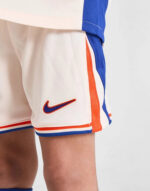 Youth soccer shorts with Nike logo, white with blue and orange accents.