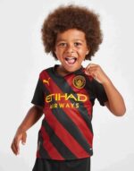 Kids football jersey Manchester City away 2022/23, authentic youth soccer kit with club logo and tea.