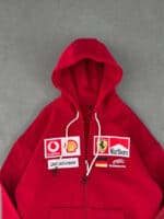 Oversized red hoodie with racing-inspired sponsor patches and Ferrari logo. Perfect for streetwear f.