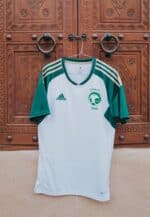 Saudi Arabia football jersey with team logo and Adidas stripes, perfect for fans and players.