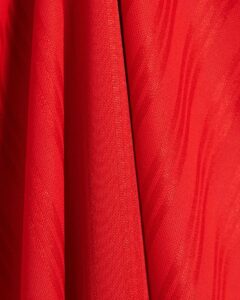 Red Adidas Adicolor T-shirt fabric close-up, detailed texture and stitching.