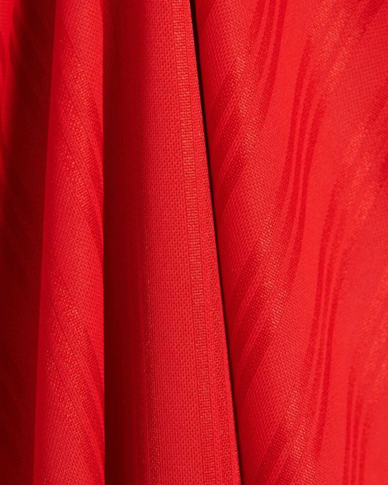 Red Adidas Adicolor T-shirt fabric close-up, detailed texture and stitching.