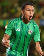 Northern Ireland football player wearing 2023/24 home jersey, celebrating victory.
