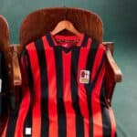 Authentic AC Milan football jersey with red and black vertical stripes, featuring club crest and Pum.