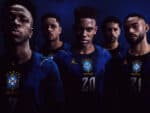 Group of five Brazilian soccer players in blue jerseys posing in a dark studio.