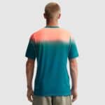 Back view of a person wearing a teal-to-coral gradient athletic shirt, standing against a light gray background.