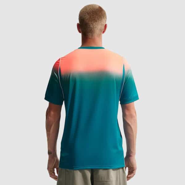 Back view of a person wearing a teal-to-coral gradient athletic shirt, standing against a light gray background.