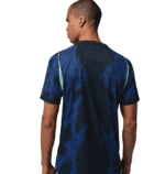 Back view of a man wearing a blue patterned athletic shirt, short sleeves, on a white background.