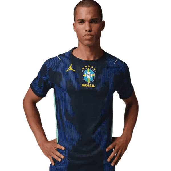 Man wearing a blue Brazil national soccer jersey, standing with hands on hips against a white background.
