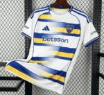 White Boca Juniors football jersey with blue and yellow stripes, sponsor 'betsson', CABJ crest, hanging on a hanger.