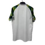 White polo shirt with green tropical leaf sleeves on a hanger, back view.