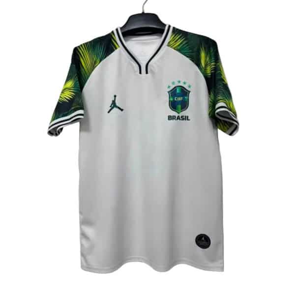 White Brazil national football team jersey with green-yellow palm-pattern sleeves hanging on a hanger, featuring CBF crest and Jordan logo on the chest.