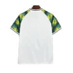 Back view of a white short-sleeve shirt with tropical palm leaf patterned sleeves in green and yellow.
