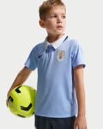 Boy in a light blue soccer jersey with a crest, holding a bright neon-green soccer ball