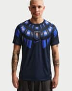 Male model wearing a navy blue football jersey with a shield crest and blue geometric patterns on the chest area.