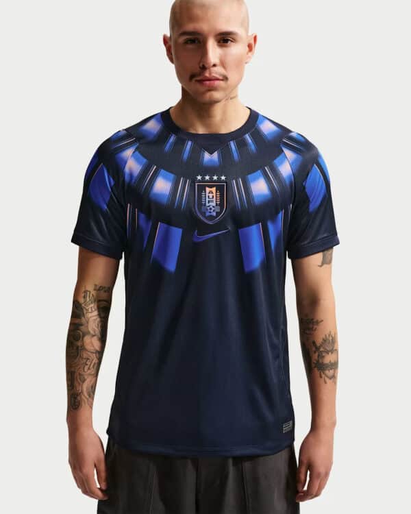 Male model wearing a navy blue football jersey with a shield crest and blue geometric patterns on the chest area.