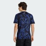 Back view of a person wearing a black shirt with bright blue swirling patterns against a light gray background.
