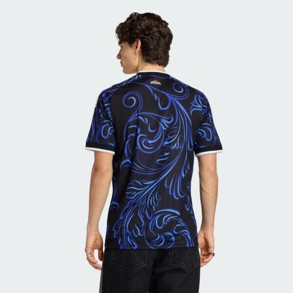Back view of a person wearing a black shirt with bright blue swirling patterns against a light gray background.