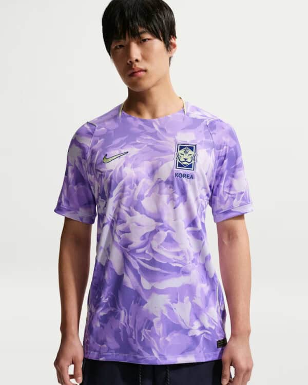 Purple camouflage soccer jersey with Korea crest and Nike swoosh worn by a male model; front view shows design details.