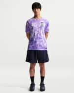 Male model wearing a purple camouflage Korea soccer jersey with navy shorts and purple sneakers, standing upright against a light background.