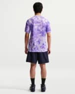 Back view of a person wearing a lavender tie-dye short-sleeve shirt and navy athletic shorts, facing away.