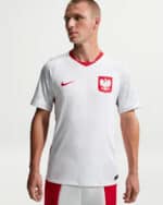 Male athlete wearing a white Poland national team jersey with red crest and Nike swoosh on the chest, facing left.