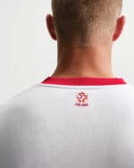 Back view of a person wearing a white jersey with a red collar and the POLSKA emblem on the upper back.