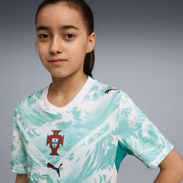 Young girl wearing a light turquoise Portugal soccer jersey, looking at the camera.