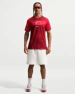 Athlete wearing a red Turkish-flag jersey, white shorts, and white sneakers, standing with hands at sides.