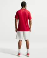 Back view of a person wearing a red athletic T-shirt, white shorts, white socks, and red sneakers, standing with feet apart.