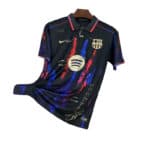 Black FC Barcelona soccer jersey with red and blue abstract streaks on a hanger, featuring the club crest and Spotify logo.