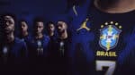 Group of Brazil national football team players standing in dark blue jerseys with crest and BRASIL text visible on the shirts.