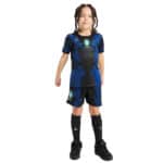 Young child wearing a blue and black Brazil national team soccer kit with matching shorts and black socks and cleats.