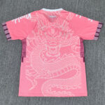 Back view of a bright pink athletic shirt featuring a large white dragon graphic across the back, white collar, and purple plaid sleeve bands.